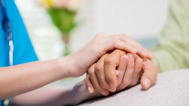 Pflegerin hält Hand - Sinnbild für akute Hauskrankenpflege